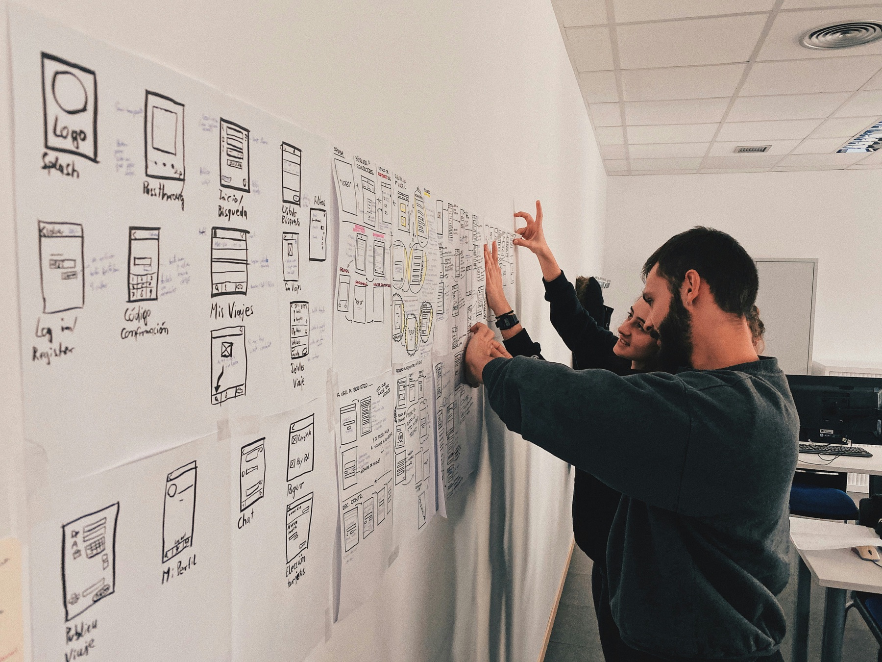A team arranging product flows and wireframes on a studio wall
